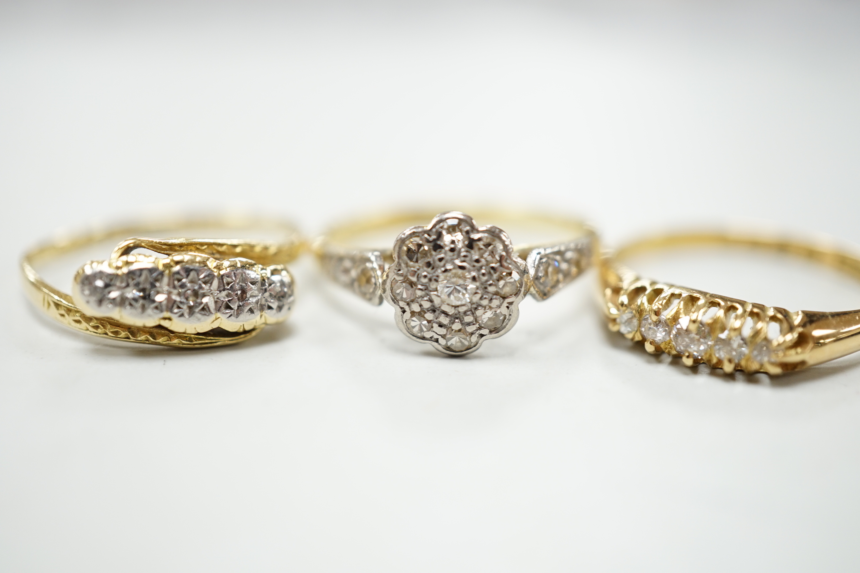 Three assorted 18ct and diamond cluster set rings including a late Victorian five stone diamond chip half hoop, gross weight 7.9 grams.